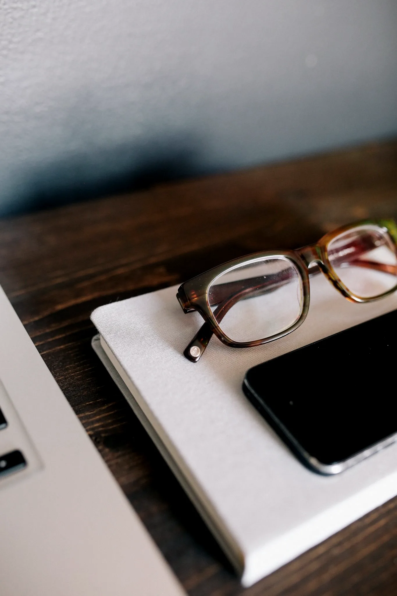 A phone and laptop side by side on a dark desk, the two device surfaces where account session activity shows up.