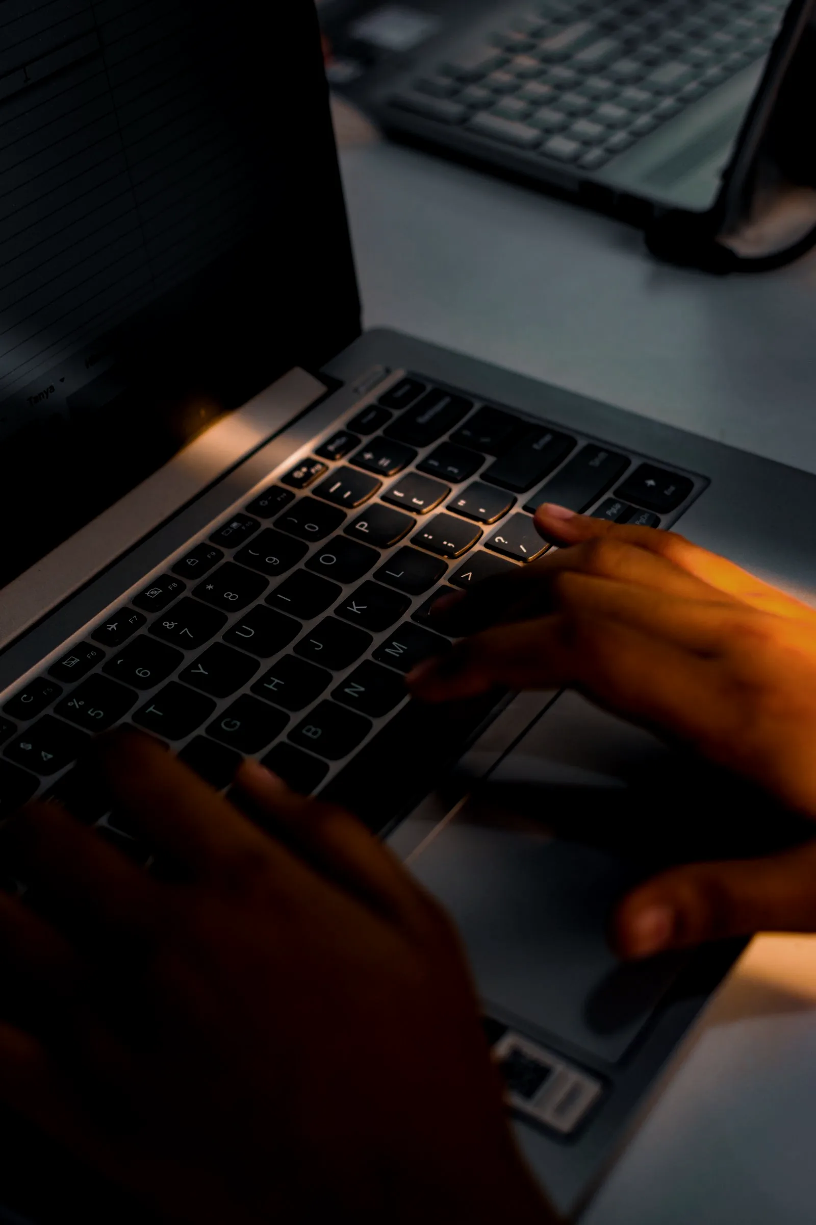 A person sitting in a dim office staring at a laptop login screen, the reset that keeps failing to stop the leak.